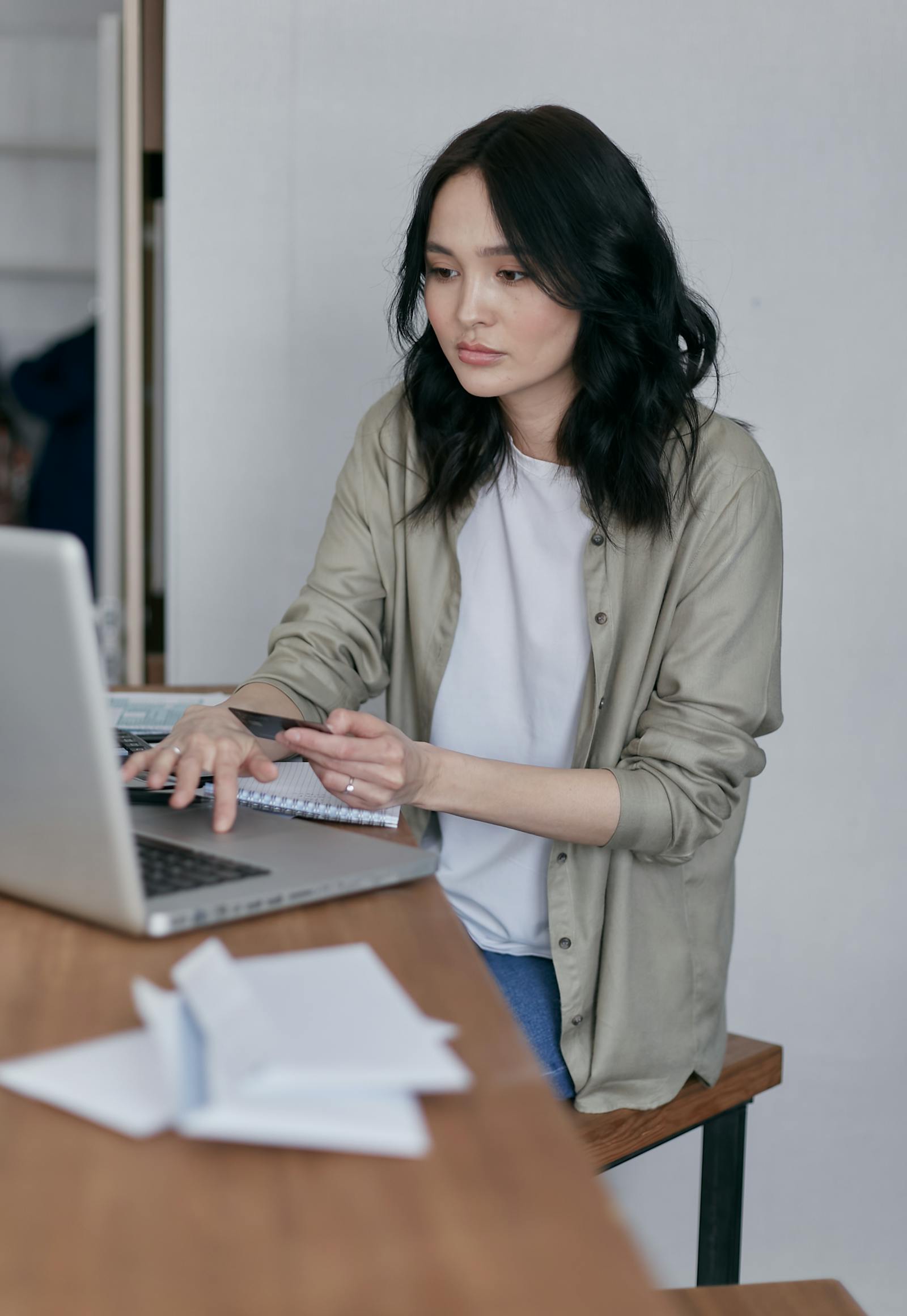 A woman using a credit card and laptop for an online payment.